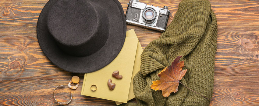 Das Hörgerät in herbstlicher Collage mit Hut, Pullover und Fotokamera